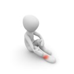 A white 3D figure sitting on the ground holding their ankle, with a red spot showing pain or injury on their foot.