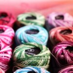 Colorful spools of embroidery thread in pink, green, blue, and other bright colors arranged together for crafting