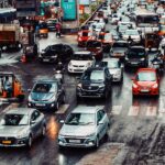 A busy city street filled with many colorful cars, trucks, and buses stuck in heavy traffic during a rainy day