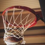 Basketball going through hoop with net, showing a successful shot from below the basket