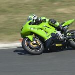 A bright green motorcycle with a rider in matching gear leans into a turn on a racetrack at high speed