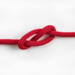 A red braided rope with a simple knot tied in the middle against a white background